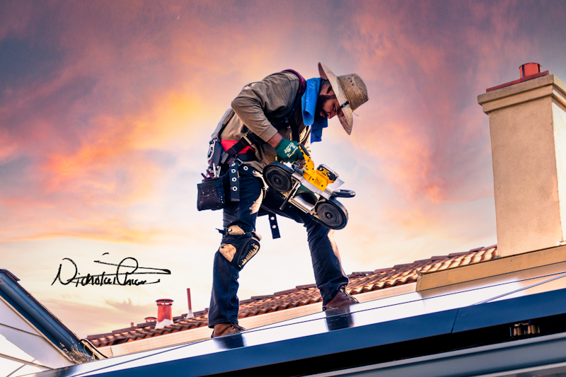 A man on a roof carrying an electric saw